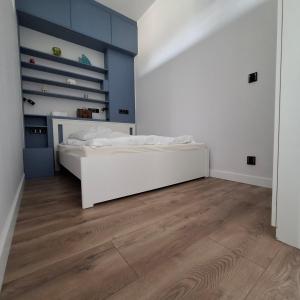 a bedroom with a white bed and a wooden floor at Century Apartment in Wrocław +4 photos