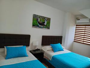 een slaapkamer met twee bedden en een foto van een kalkoen aan de muur bij Tesita's House habitación doble in Puerto Baquerizo Moreno