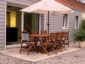 - une table et des chaises en bois avec un parasol sur la terrasse dans l'établissement La maison de la Terre d Opale, à Saint-Inglevert