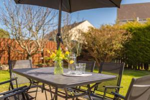einen Tisch mit einer Vase Blumen und einem Regenschirm in der Unterkunft Serenity House, Whitehall Ballycastle in Ballycastle