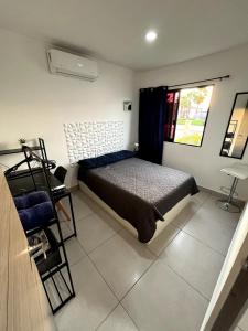 ein Schlafzimmer mit einem Bett und einem Stuhl und einem Fenster in der Unterkunft Refugio Perfecto con Alberca y seguridad Cerca Galerías! in Mazatlán