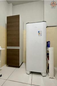 Cette chambre dispose d'une porte en bois et d'un réfrigérateur blanc. dans l'établissement AVENIDA PAULISTA - QUARTO CASAL em Apartamento compartilhado, à São Paulo