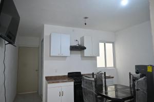 a kitchen with white cabinets and a glass table at Departamentos La Soledad in Huejotzingo