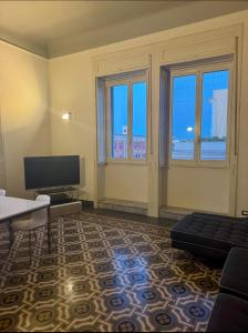 - un salon avec un canapé, une télévision et des fenêtres dans l'établissement Best Stay-Theatre Suite Apartment, à Bari