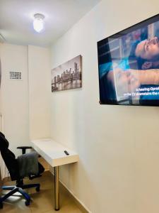 een kamer met een bureau en een tv aan de muur bij 47 on Hyde Park in Kaapstad