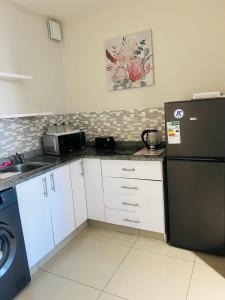 een keuken met een zwarte koelkast en een magnetron bij 47 on Hyde Park in Kaapstad