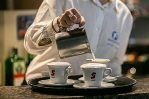 a chef pouring coffee into two cups on a tray at Alloggi Centrale in Porto Tolle