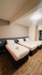 three beds in a room with wooden floors at Mulligan Hotel in Dublin