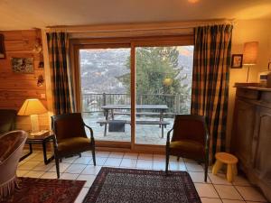 a living room with a sliding glass door with a table at Chalet de charme à Vallouise in Le Poët