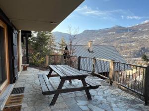 a wooden picnic table on a balcony with a view at Chalet de charme à Vallouise in Le Poët