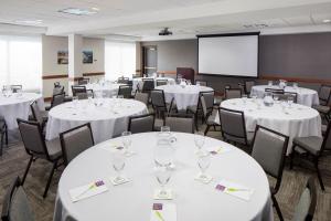 a conference room with white tables and chairs and a screen at Hyatt Place Atlanta Airport North in Atlanta