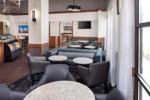 a waiting room with tables and chairs and a tv at Hyatt Place Atlanta Airport North in Atlanta