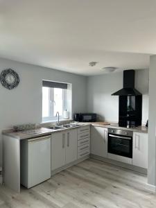a kitchen with white cabinets and a sink and a stove at Flat At 34 in Street