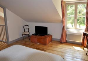 ein Schlafzimmer mit einem Bett, einem TV und einem Stuhl in der Unterkunft Chateau de Lourdes in Saint-Méloir-des-Ondes