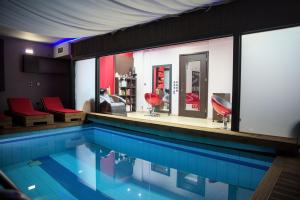 a swimming pool with red chairs and a bar at Myriam Spa & Luxury Suites in Monemvasia