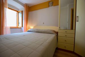 a bedroom with a bed and a dresser and a window at House Nonina kuca in Rab