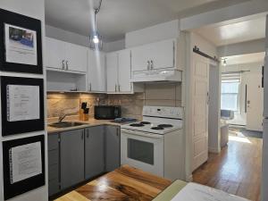 a kitchen with white cabinets and a stove top oven at Espace Couronne by Hébergements DCL in Quebec City