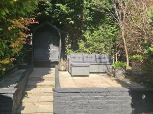 a couch sitting in a gazebo in a garden at Shakespeare’s Nest in Prescot