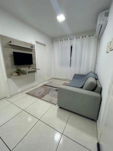 ein Wohnzimmer mit Sofa und Fernseher in der Unterkunft Aconchegante Cantinho 202 in Penha