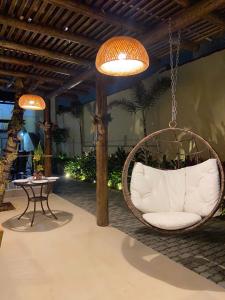 a room with a hanging chair and a table at Pousada Caminho da Passagem in Cabo Frio