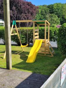 un parque infantil con un tobogán amarillo en un patio en The Sunny Bunny Holiday Home, en Ballantrae
