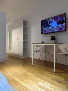 a living room with a table and a tv on the wall at München Messe Apartment in Munich