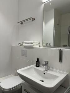 a white bathroom with a sink and a toilet at München Messe Apartment in Munich