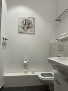 a white bathroom with a toilet and a sink at München Messe Apartment in Munich +22 photos