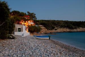a person standing on a rocky beach with a boat at Pefkos Beach House 2 in Kámpos