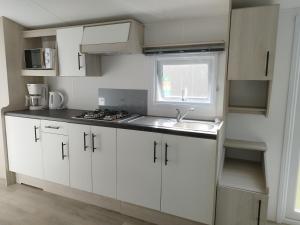 a kitchen with white cabinets and a sink and a window at Magnolia in Cambron-Casteau
