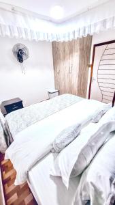 a bedroom with a large bed with white sheets and pillows at Cool Breeze Penthouse - Nati Apartment in Kisumu