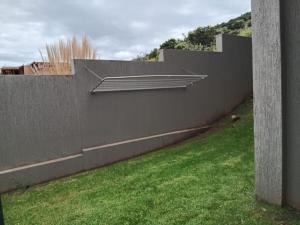 einen Betonzaun mit einer Mauer und einem grünen Hof in der Unterkunft Bachelor cottage on an estate in Eikenhof + 1 Foto
