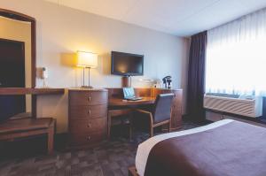a hotel room with a bed and a desk with a laptop at Hotel Continental Centre-Ville in Val-dʼOr