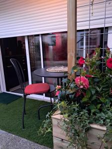 a patio with a table and a chair and some flowers at Le Petit Parisien- Bienvenue - Netflix - Terrasse - Parking - Porte de Paris - Climatisation - Guide visite à Paris OFFERT in Pantin +5 photos