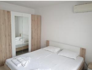 a bedroom with a white bed and a mirror at Apartament Magi in Sozopol