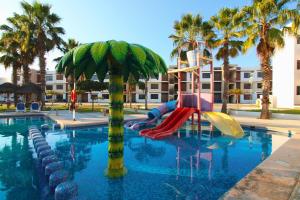 een waterglijbaan in een zwembad met palmbomen bij Departamento Close to Beach - Azul pacifico in Mazatlán