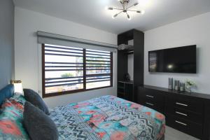 een slaapkamer met een bed en een flatscreen-tv bij Departamento Close to Beach - Azul pacifico in Mazatlán