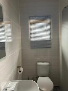 Un baño blanco con inodoro y lavabo. en At JayRose, en Kimberley
