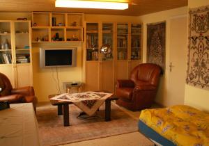 sala de estar con sillas, mesa y TV en Villa Lavendel, en Gondiswil