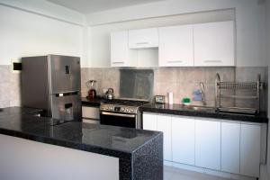 a kitchen with white cabinets and black counter tops at Kampu Wasi - Casa de Campo in Pachacamac