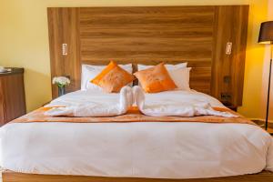 - un grand lit avec des oreillers orange et blancs dans l'établissement Karen Plains Hotel Nairobi, à Nairobi