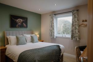 a bedroom with a large bed and a window at Cosy wee cottage -modern, open plan, parking, EV in Glencaple