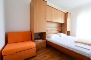 1 dormitorio con 1 cama y 1 silla naranja en Apartments Zlatko, en Donje Selo