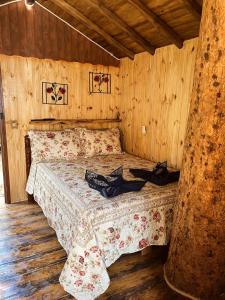 a bedroom with a bed in a wooden room at Cabana da àrvore Refúgio Jaguary in Monte Verde