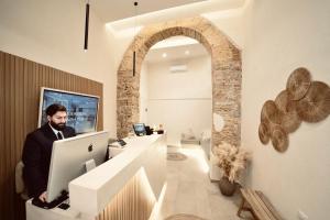 a man sitting at a desk with a laptop computer at Palermo Inn Boutique Arte in Palermo
