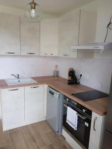 a kitchen with white cabinets and a wooden counter top at Maison partagée - Studio bas in Beauvais