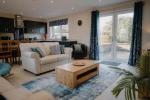 a living room with a couch and a coffee table at Cosy wee cottage -modern, open plan, parking, EV in Glencaple