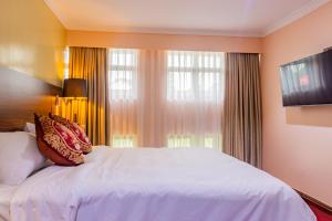 a bedroom with a white bed and a large window at Karen Plains Hotel Nairobi in Nairobi
