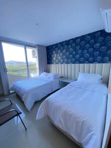 Playa Bello HorizonteU-GO Oasis: Encanto y Confort Frente al Mar en Santa Marta的一间卧室，有两张床和一面蓝色的墙 更多14张照片