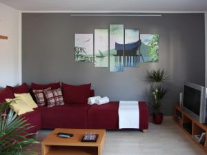 ein Wohnzimmer mit einem roten Sofa und einigen Gemälden in der Unterkunft Ferienwohnung Lamm in Rümmingen